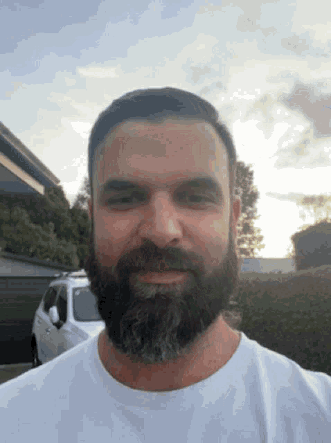 a man with a beard and a white shirt is smiling