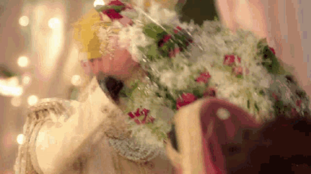 a bride and groom are kissing at their wedding and the bride has a crown of flowers on her head .