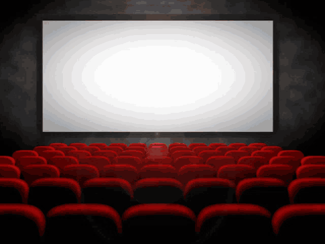 an empty theater with red seats and a white screen