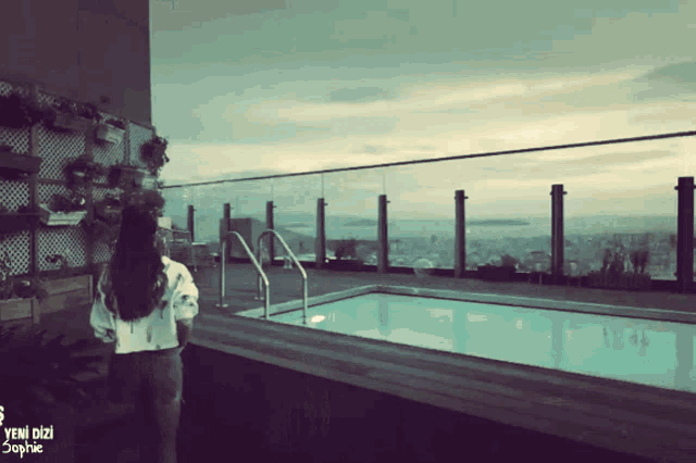 a woman stands on a balcony overlooking a swimming pool with the words yeni dizi sophie written below her