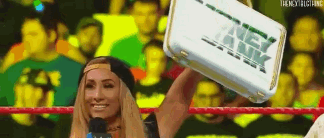 a woman in a wrestling ring is holding a briefcase in the air .