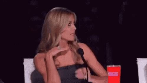 a woman in a black strapless dress is sitting in front of a microphone .
