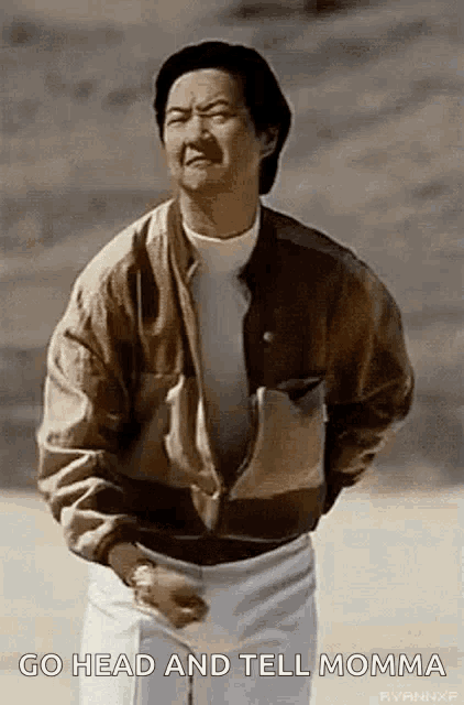 a man in a brown jacket and white shorts is standing on a beach and talking to his mom .