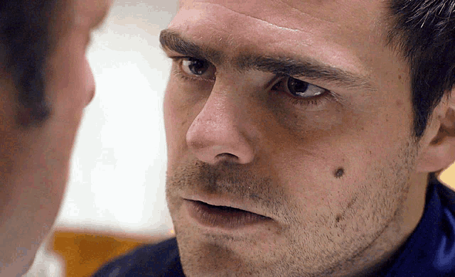 a close up of a man 's face with a black spot on his forehead