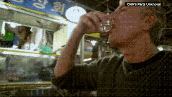 a man drinking from a glass with cnn 's parts unknown written on the bottom