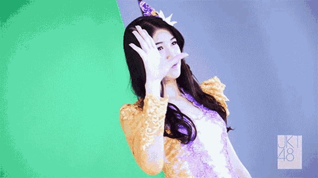 a woman in a purple and gold dress is waving her hand