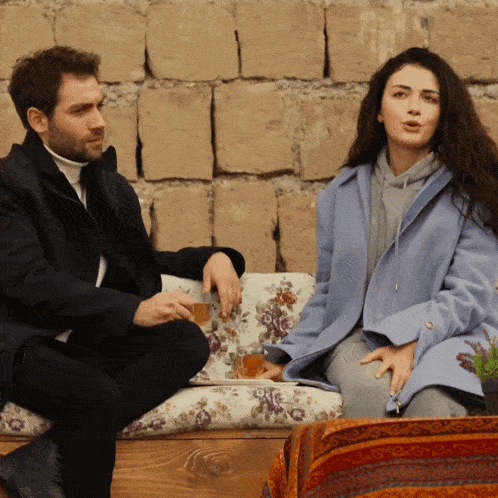 a man and a woman are sitting on a couch talking to each other