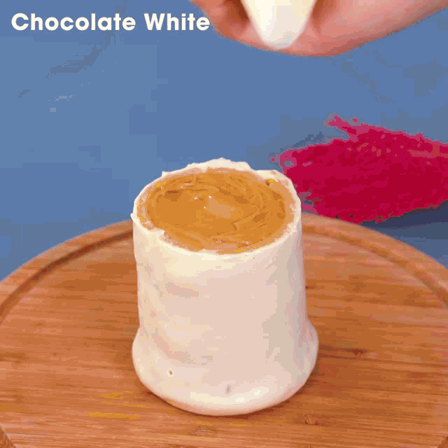 a person spreading chocolate whipped cream on top of a cake