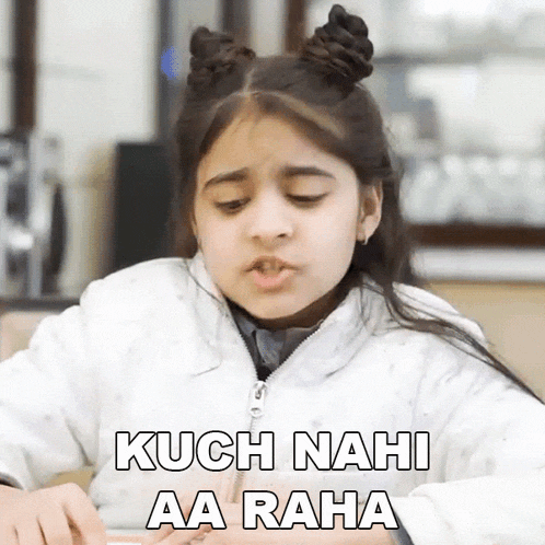 a little girl is sitting at a table with the words kuch nahi aa raha written on it .