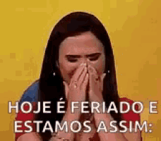a woman is covering her mouth with her hands and says `` hoje e feriado e estamos assim '' .