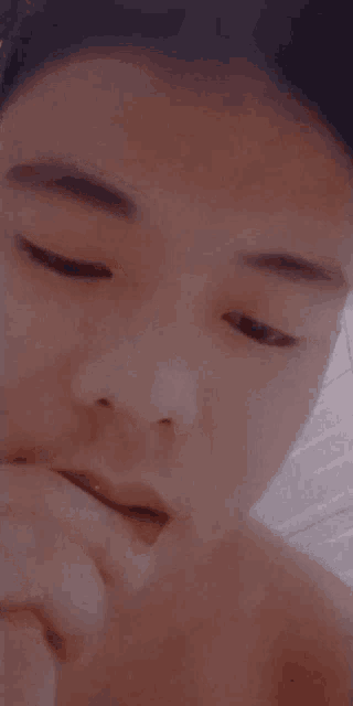 a close up of a person 's face with their eyes closed and their hand on their mouth .