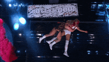 two wrestlers are laying on the floor in front of a sign that says hollywood