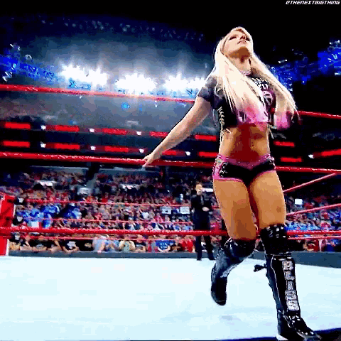 a woman is standing in a wrestling ring wearing knee pads and knee pads .