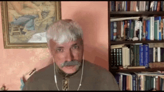 a man with a mustache is wearing headphones in front of a bookshelf filled with books .