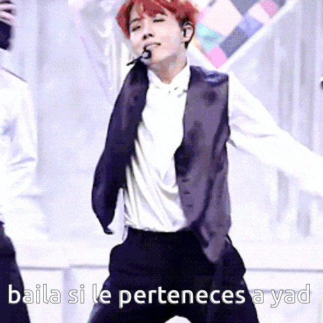 a man in a suit is singing into a microphone with the words baila si le perteneces a yad written below him