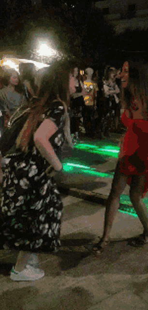 two women are dancing in front of a green light