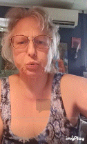 a woman wearing glasses and a tank top is taking a selfie