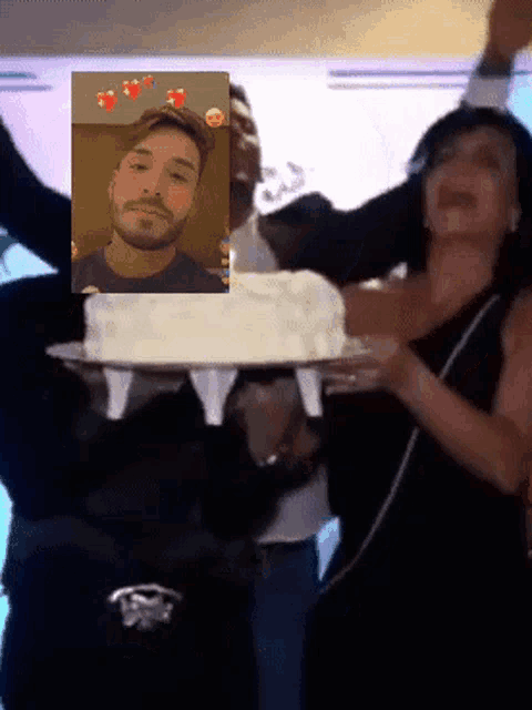 a man and a woman are holding a cake in front of a man 's face