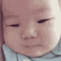 a baby is making a funny face with his eyes closed and his mouth open .