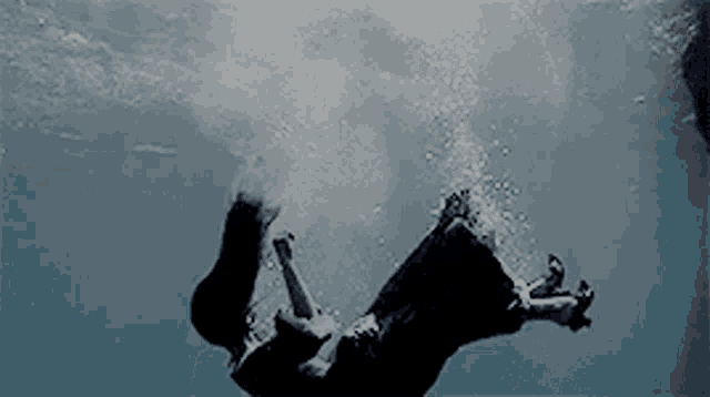 a woman is falling into the water and making bubbles .