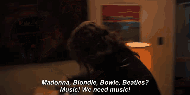 a woman sitting on a bed talking about madonna blondie bowie beatles