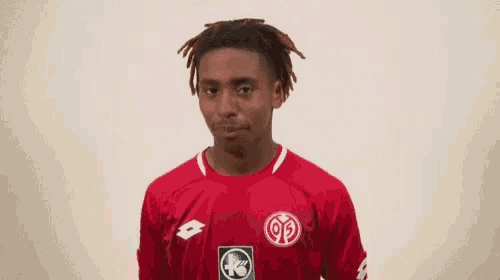 a young man wearing a red shirt with a lotto logo on it gives a thumbs up