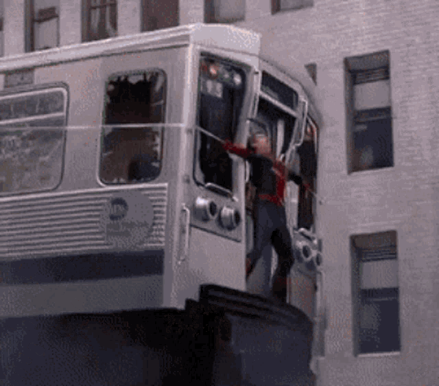 a man in a spiderman costume stands on top of a subway car