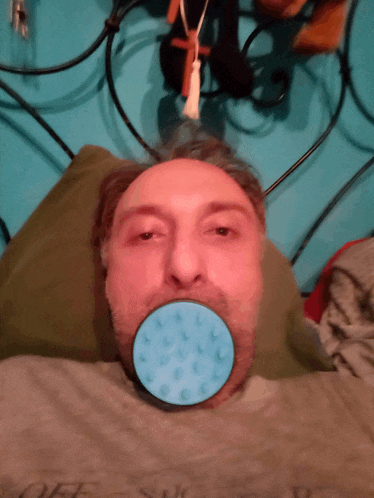 a man is laying on a bed with a blue circle in his mouth
