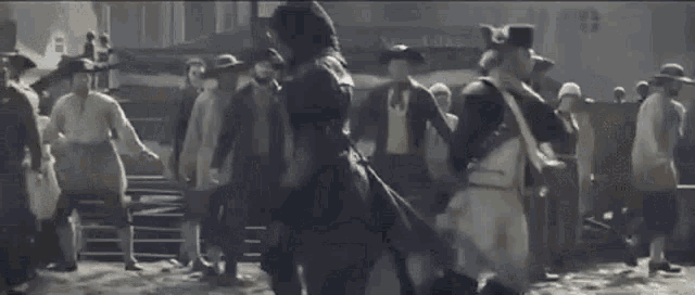 a man in a napoleonic hat is standing in front of a crowd of people .