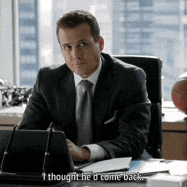 a man in a suit and tie sits at a desk with a tablet and says i thought he 'd come back