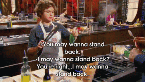 a man in an apron is cooking and says " you may wanna stand back i may wanna stand back "