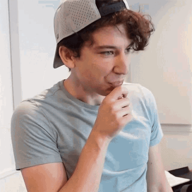 a young man wearing a baseball cap and a gray shirt