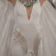 a woman in a white dress with a blue necklace is dancing .