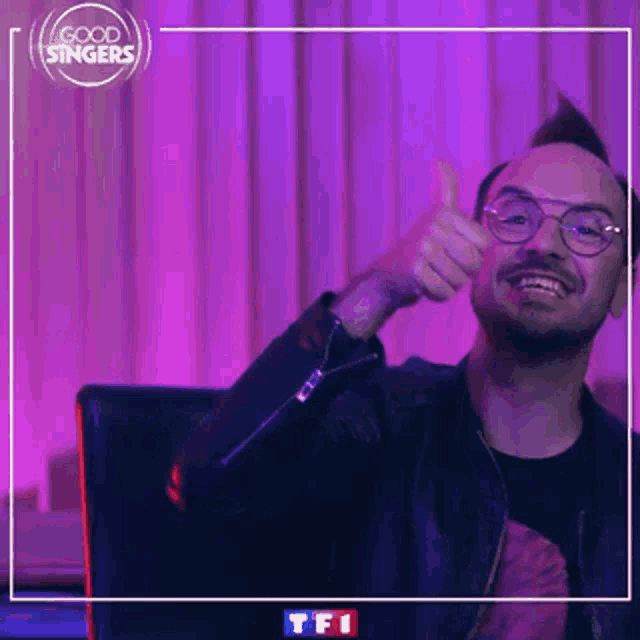 a man wearing glasses and a leather jacket is giving a thumbs up