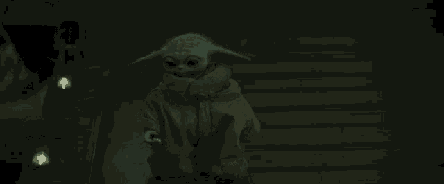 a baby yoda is walking down stairs in the dark .