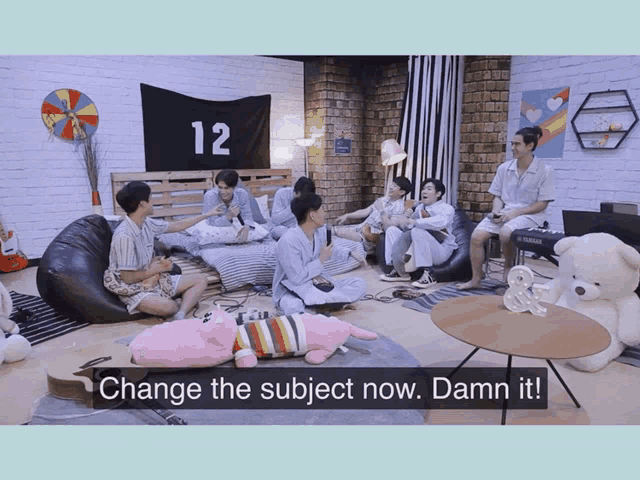 a group of young men are sitting around a table with a sign that says change the subject now