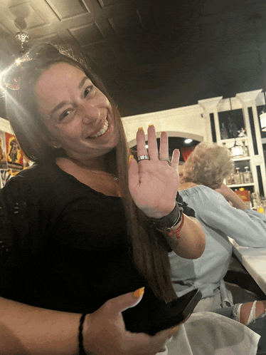 a woman with a ring on her finger smiles while holding a cell phone