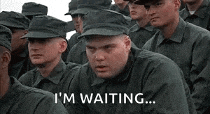 a group of soldiers are sitting in a row and one of them is saying `` i 'm waiting '' .