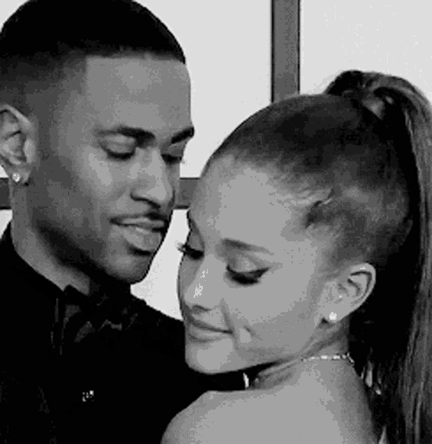 a man and a woman are looking into each other 's eyes in a black and white photo .