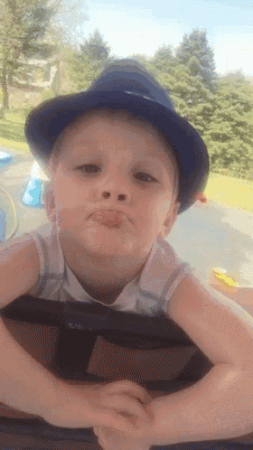 a young boy wearing a blue hat is making a face