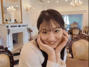 a woman is sitting at a table with her hands on her face and smiling