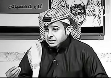 a black and white photo of a man with arabic writing on the wall behind him