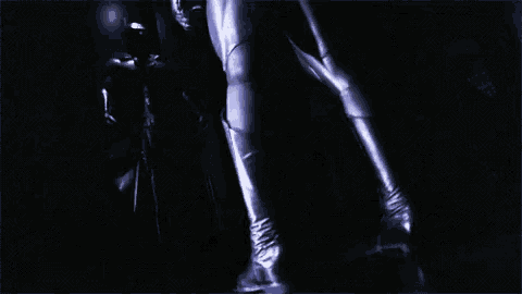 a person in a dark room with a purple jacket