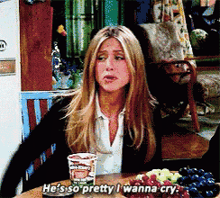 a woman sits at a table with a cup of ice cream and says he 's so pretty i wanna cry .