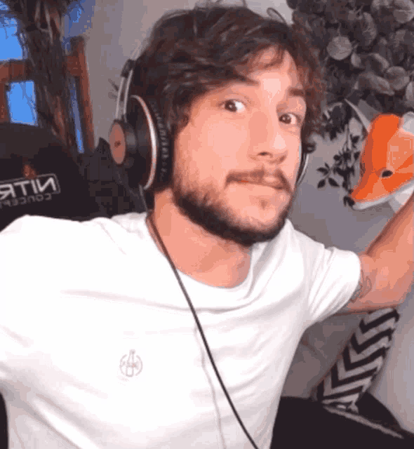a man wearing headphones is standing in front of a chair that says " aetii "