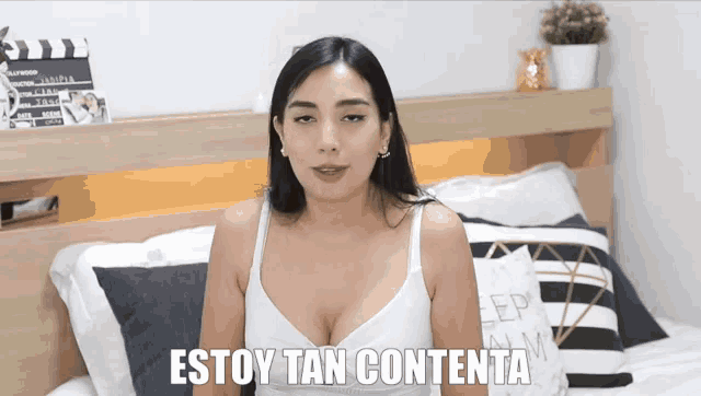 a woman sitting on a bed with the words estoy tan contenta written on the bottom