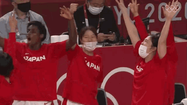 a group of people wearing face masks and red shirts that say japan