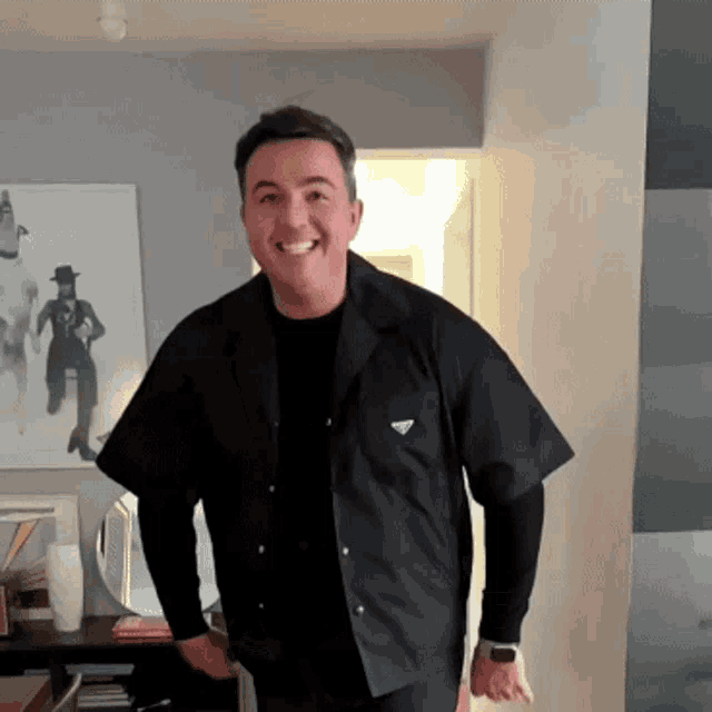 a man wearing a black shirt with a triangle logo on the front is smiling