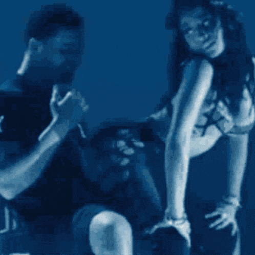 a man is singing into a microphone while a woman is dancing behind him