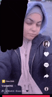 a woman wearing a hijab and a hoodie is taking a selfie on a cell phone .